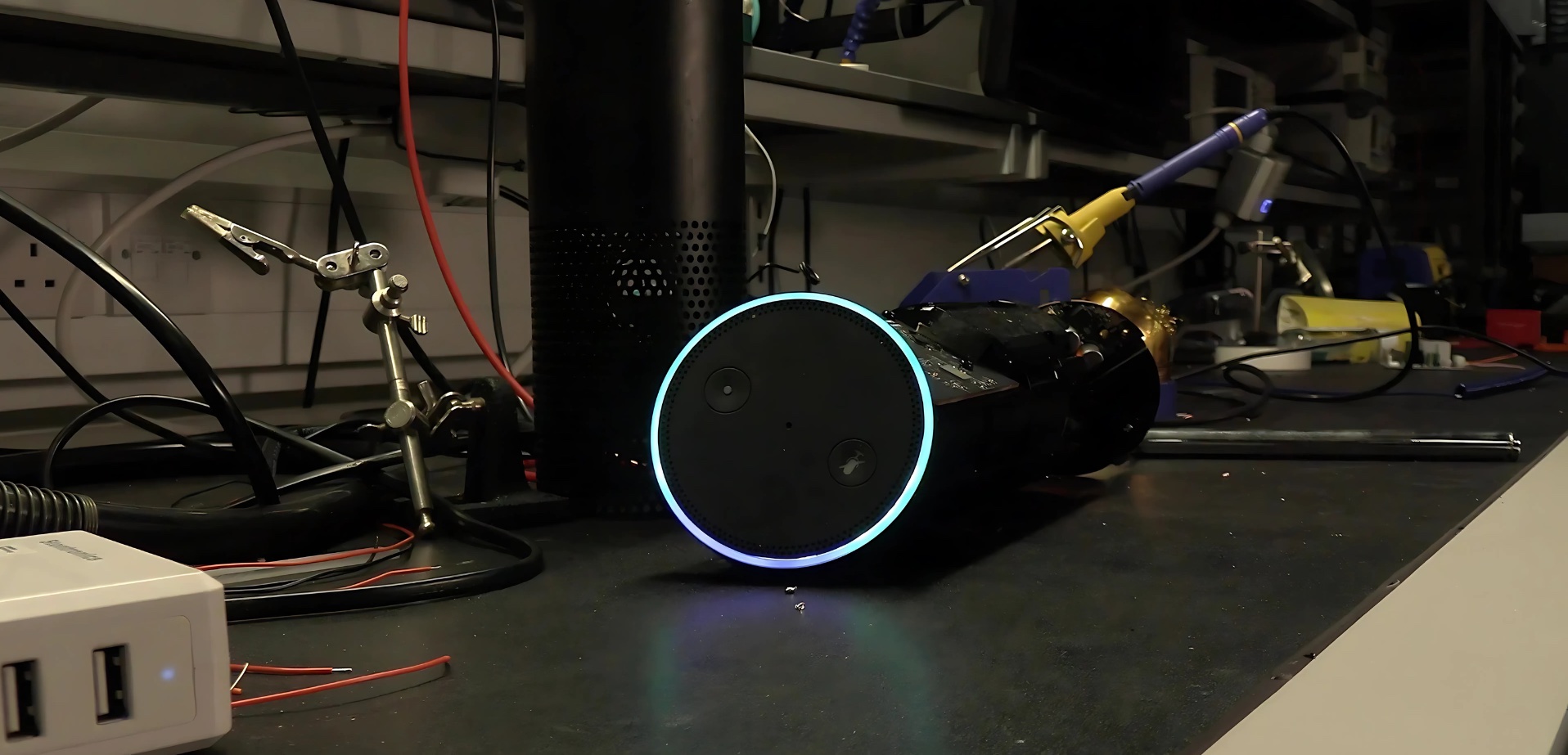 An image of an Amazon Echo being disassembled on a workbench.