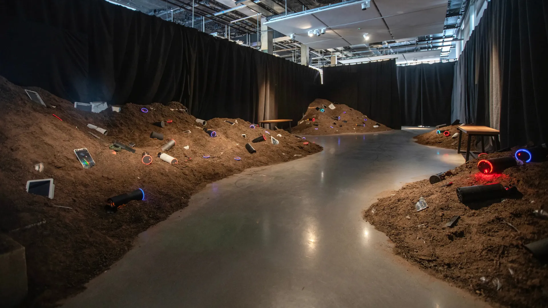 Installation view of the work, showing 6 tonnes of soil in a room, with 200 buried smartphones and smart speakers